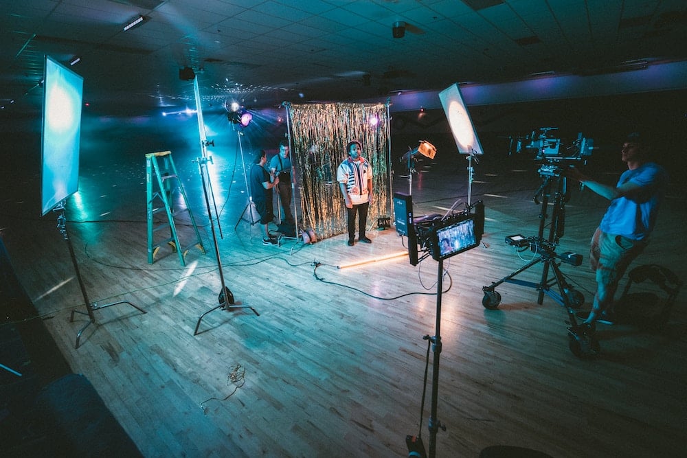 Plateau de tournage avec des éclairages et des caméras et au milieu, un homme (auditoire)