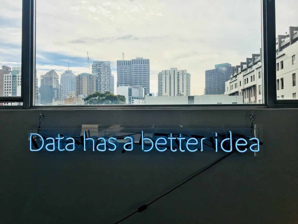 Lettres en néon formant la phrase "Data has a better idea" devant une fenêtre avec une vue sur des gratte-ciels (en relations publiques)