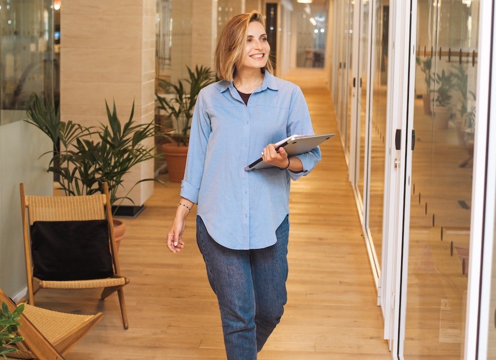 Attitude responsable | Femme qui marche dans un corridor avec une tablette électronique dans la main gauche